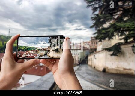 Turista che scatta foto della vista della strada a Praga, Repubblica Ceca. Uomo che tiene il telefono e fotografare la strada con una splendida vista sulla città storica Foto Stock
