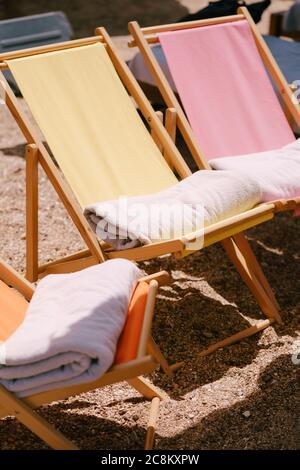 Sedie a sdraio in legno, lettini e teli mare sulla spiaggia di sabbia. Foto Stock