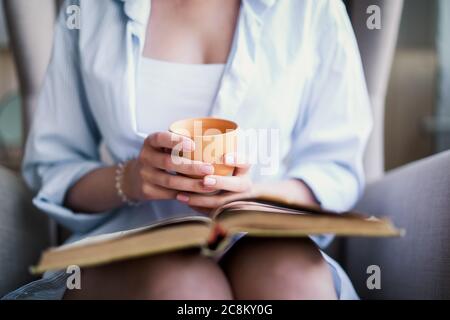 Bella ragazza che legge un libro a casa. Intrattenimento all'interno Foto Stock