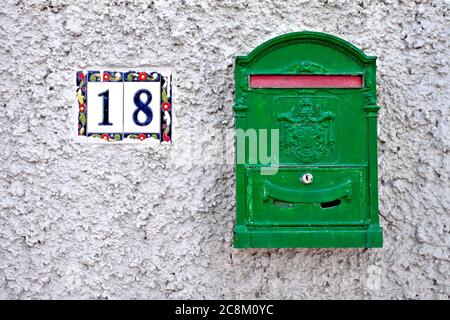 Una casella di lettera verde e il numero 18 su una parete grigia. Foto Stock