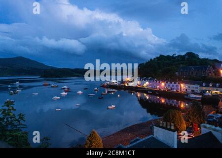 Bella piccola città portuale di notte, il porto di Portree di notte, all'Isola di Skye. Piccole barche da pesca e riflessi sull'acqua. Foto Stock