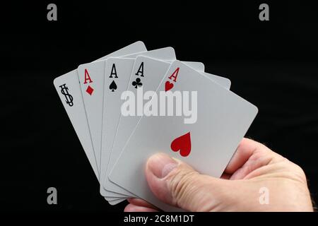 Mano che tiene carte da gioco di poker su sfondo nero. Foto Stock