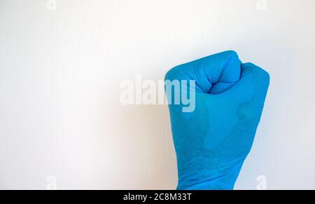 Mano aggrappata in un guanto medico blu su sfondo bianco. Spazio vuoto per il testo. Foto Stock