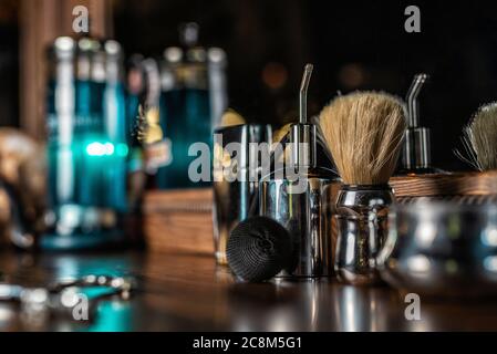 Spazzola cromata e uno spray d'acqua, sullo sfondo degli accessori per un parrucchiere. Barbiere, tavolo vintage, sfocatura morbida. Foto Stock