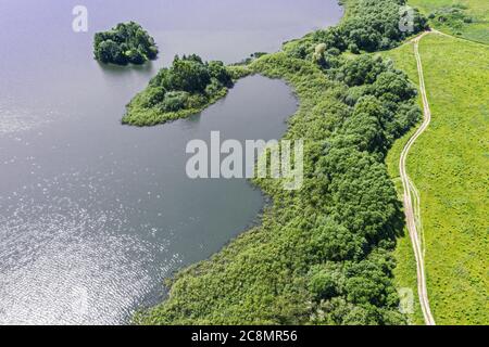 verde campagna paesaggio con strada sterrata sulla riva del lago. vista aerea dal drone volante Foto Stock