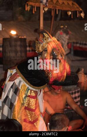 Foto drammatica di ballerini Kecak vestiti con colori colorati e vestiti in costumi tradizionali dai colori vivaci che eseguono la danza balinese del Tempio Ramayana Indù. Foto Stock