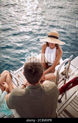 Amici che si godono il tramonto a poppa di uno yacht in un tempo meraviglioso Foto Stock