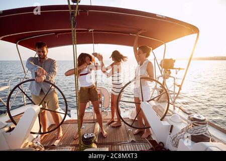 Allegra compagnia che balla su uno yacht al tramonto Foto Stock