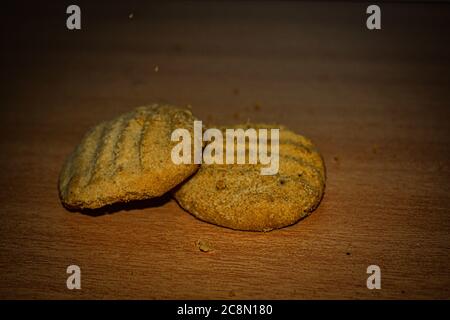 Una pila di deliziosi biscotti rotondi di grano con alcune briciole isolate su tavola marrone Foto Stock