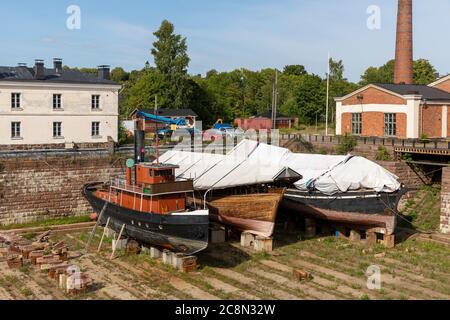 Navi d'epoca in attesa di restauro su un molo a secco sull'isola di Suomenlinna vicino a Helsinki. L'acqua viene portata a bacino quando le navi sono pronte per essere spostate in mare. Foto Stock