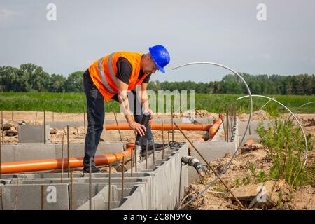 Costruttore che controlla la fondazione bungalow della casa, concetto di costruzione Foto Stock