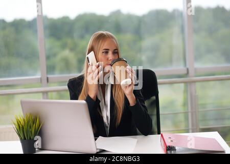 chat bionde sul telefono bere caffè Foto Stock