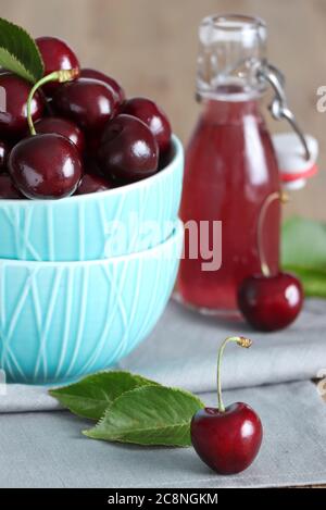 ciliegie dolci fresche in recipiente e bottiglia di vetro con succo Foto Stock