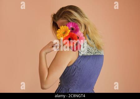 Giovane donna allegra con abiti in denim e fiori camomilla in mani Foto Stock