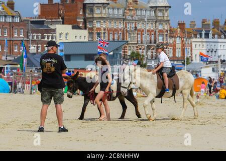 Weymouth, Dorset, Regno Unito. 26 luglio 2020. Regno Unito Meteo. I bambini si divertono con un giro in asino sulla spiaggia presso la località balneare di Weymouth in Dorset, in una mattina di caldo sole frizzante. Immagine: Graham Hunt/Alamy Live News Foto Stock