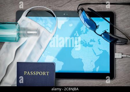 Viaggio sicuro durante una crisi pandemica, desktop con maschera, mappa e altri accessori Foto Stock