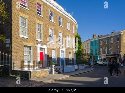 Eleganti terrazze su una strada curva a Portobello Mews, Notting Hill, Londra, in un pomeriggio autunnale splendidamente soleggiato. Atmosfera rilassata. Foto Stock