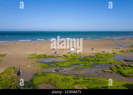 I turisti catturati in stile Lowry sullo sfondo della spiaggia di Scarborough in una bella e soleggiata giornata estiva. (2) Foto Stock