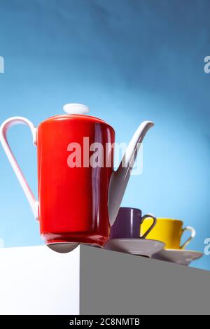 La teiera per caffè rosso e due tazze per la caffetteria si trovano su un cubo bianco Foto Stock