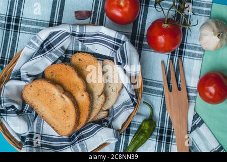 Cibo fresco naturale, ingredienti vegetariani italiani, pasta di spaghetti con aglio e pane tostato su un cesto su un panno da tavola, forchetta di legno di pepe verde Foto Stock