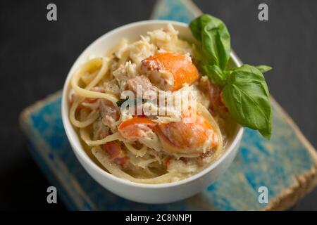Una ciotola di linguine di granchio fatta con la carne bianca da un granchio marrone, Cancer pagurus, che comprende crema, aglio, basilico, peperoncino, olio d'oliva e nero Foto Stock