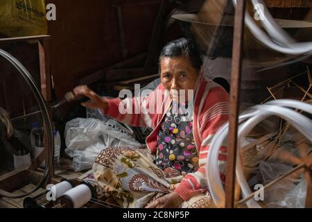 Lago Inle, Myanmar - Febbraio 2020: La donna birmana gira il filo su una ruota di filatura tradizionale nel villaggio locale. Fibre di loto e di seta sono tessute per Foto Stock