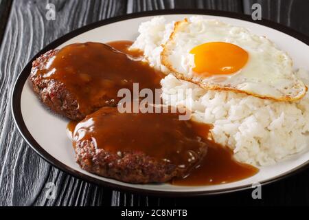 Piatto tradizionale hawaiano di riso loco Moco, polpettine di manzo macinato e uovo con sugo di carne su un piatto sul tavolo. Orizzontale Foto Stock