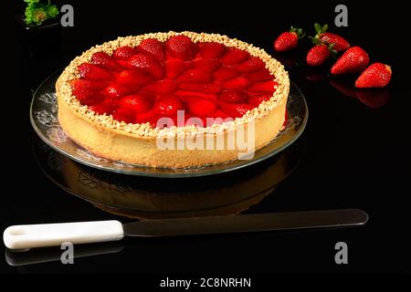 fetta di torta di fragole con noci di anacardi macinate su un tavolo di vetro scuro Foto Stock