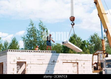 Lavoratore di costruzione che installa il pannello di soletta di pavimento di calcestruzzo nel cantiere. Secondo piano casa pavimento cemento posa in lastra Foto Stock