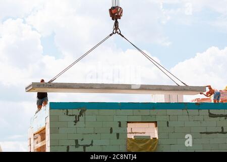 Lavoratore di costruzione che installa il pannello di soletta di pavimento di calcestruzzo nel cantiere. Secondo piano casa pavimento cemento posa in lastra Foto Stock