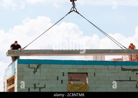 Lavoratore di costruzione che installa il pannello di soletta di pavimento di calcestruzzo nel cantiere. Secondo piano casa pavimento cemento posa in lastra Foto Stock