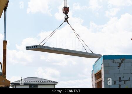 Lavoratore di costruzione che installa il pannello di soletta di pavimento di calcestruzzo nel cantiere. Secondo piano casa pavimento cemento posa in lastra Foto Stock