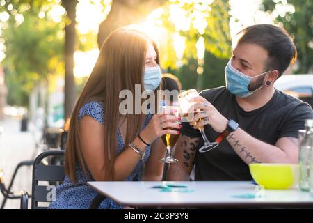 Spagna Madrid. Tostatura di coppia caucasica con birra che indossa una maschera sanitaria. Riaprire pub e club dopo quarentine coronavirus Covid-19. Uomo e donna dri Foto Stock