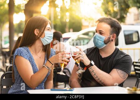 Spagna Madrid. Tostatura di coppia caucasica con birra che indossa una maschera sanitaria. Riaprire pub e club dopo quarentine coronavirus Covid-19. Foto Stock