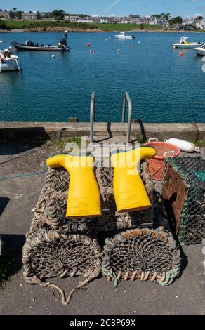 Stivali gialli wellington disposti ad asciugare su creel di aragosta nel porto, Isola di Whithorn, Dumfries & Galloway, Scozia. Foto Stock