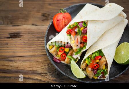 Tortilla fresche con carne di pollo e verdure sul tavolo di legno Foto Stock
