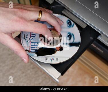 Qualcuno per guardare il film in DVD Notting Hill. DVD (acronimo di Digital versatile Disc o Digital Video Disc) è un formato di archiviazione di dischi ottici digitali inventato e sviluppato nel 1995 e rilasciato alla fine del 1996. Il supporto può memorizzare qualsiasi tipo di dati digitali ed è ampiamente utilizzato per software e altri file di computer, nonché per programmi video che utilizzano lettori DVD. I DVD offrono una capacità di memorizzazione superiore rispetto ai compact disc, pur avendo le stesse dimensioni. Foto Gippe Gustafsson Foto Stock