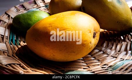 un mango fresco succoso isolato su fondo texture di bambù gocce d'acqua Foto Stock