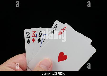 Mano che tiene carte da gioco di poker su sfondo nero. Foto Stock