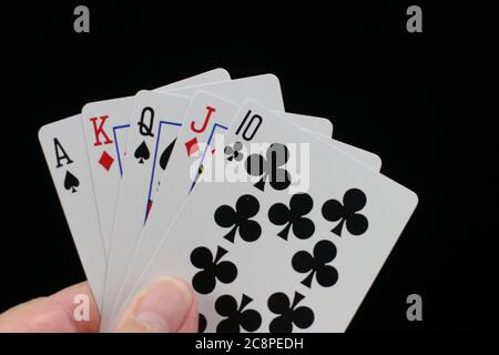 Mano che tiene carte da gioco di poker su sfondo nero con asso alto diritto. Foto Stock