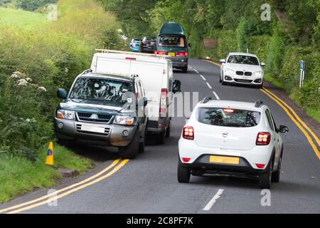 Killearn, Stirlingshire, Scozia, Regno Unito. 26 luglio 2020. I servizi di emergenza sono stati chiamati a Finnich Glen (pulpito del Diavolo) nel tardo pomeriggio per estrarre una coppia che era intrappolata. Nella foto: Le doppie linee gialle sono state introdotte nelle immediate vicinanze a causa di un parcheggio pericoloso e irresponsabile, ma nonostante questo numero di visitatori (come l'auto e il furgone a sinistra) insistono ancora sul parcheggio sulla strada, anche in curva, costringendo i veicoli a traffico in avvicinamento. Credit: Kay Roxby/Alamy Live News Foto Stock