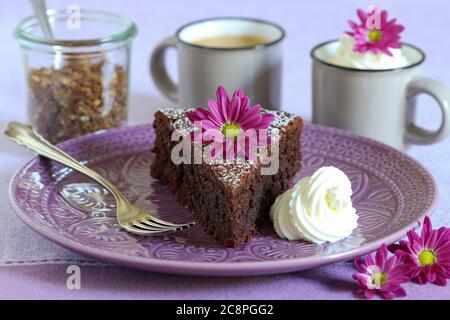 pezzo di torta al cioccolato sul piatto e fiori di crisantemo decorazione astable Foto Stock