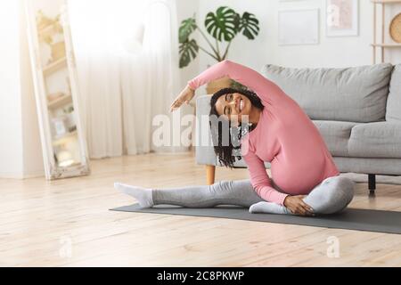 Donna incinta africana positiva che fa l'esercitazione di mattina a casa Foto Stock