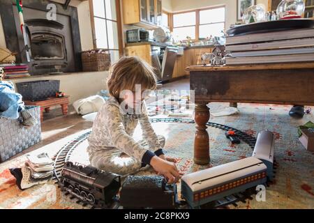 ragazzo di 4 anni che indossa pigiami che giocano con giocattoli a casa Foto Stock