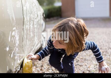 ragazzo di 4 anni che lavava un'auto nel parcheggio Foto Stock
