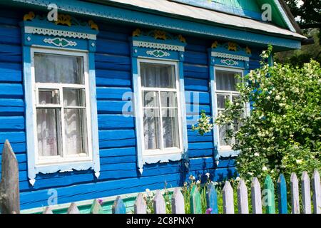 Finestre e cornici ornamentali intagliati. Casa rurale d'epoca in Bielorussia. Tradizionale stile popolare nazionale in architettura di legno. Blu e bianco Foto Stock