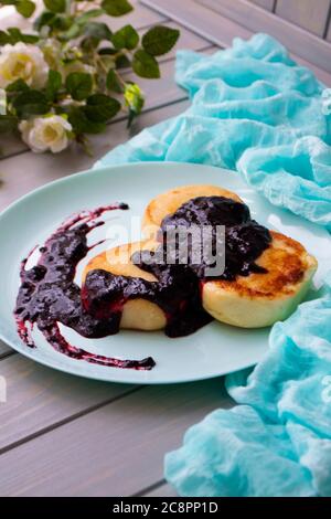 Frittelle di formaggio cottage con curry e marmellata di bolle su piatto di tè vintage, immagine verticale Foto Stock