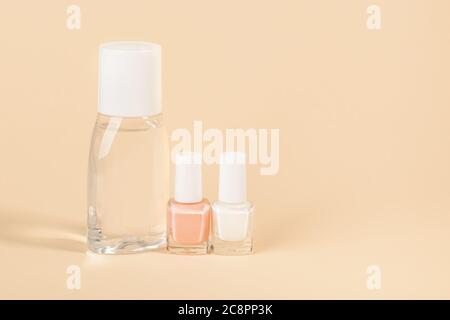Bottiglia con smalto per unghie, smalto bianco e rosa pallido su fondo di colore polveroso. Prodotti per manicure, pedicure, cura delle unghie. Spazio di copia. Foto Stock