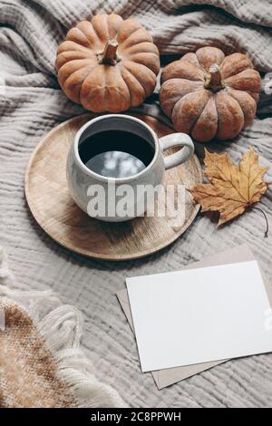 Composizione in stile autunnale. Colazione autunno ancora vita. Scena di mock-up del biglietto d'auguri vuoto con tazza di caffè, coperta di lana, foglia d'acero e zucche Foto Stock