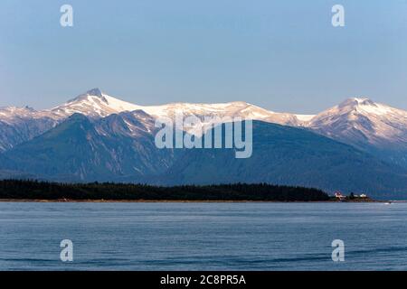 Punta Retreat Faro all'estremo nord dell'isola di Admiralty a poche miglia a nord di Juneau, Alaska con montagna nella neve sullo sfondo Foto Stock